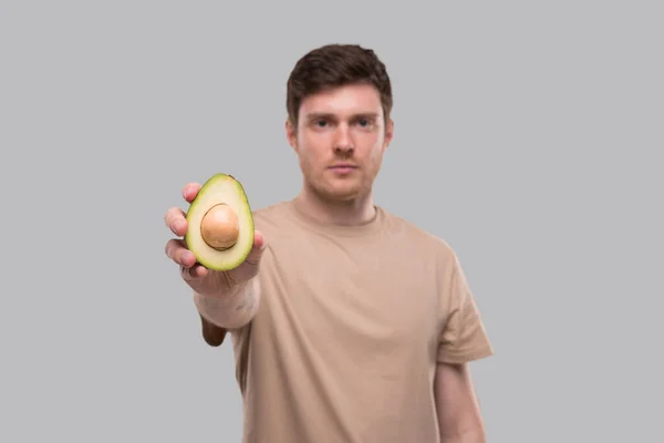 Man Toont Avocado Serious Face Geïsoleerd Avocado Doormidden Gesneden Gezond — Stockfoto