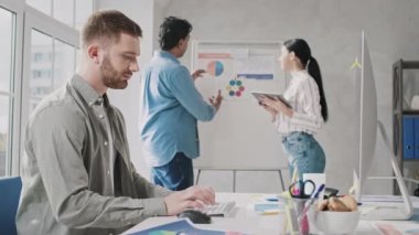 Yaratıcı Ofis 'te bilgisayar üzerinde çalışan adam. Kız ve Hintli Adam Ofiste Sunum Konuşuyor. Yaratıcı Ofis İşleri. Kırmızı ışıkta.