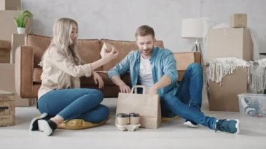 Eve yeni taşınan Fast Food paketini boşaltan çift. Yemek getiren çift. Yeni Ev Teslimatı. Evde fast food yiyen bir çift. Kırmızı ışıkta.