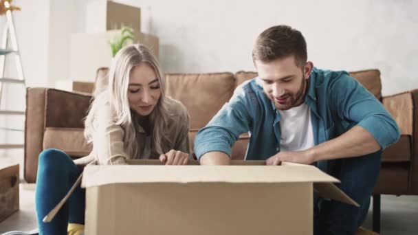 Par udpakning boks i et nyt hjem taler med hinanden. Par flyttede til nyt hjem. Pakker ud. Skud på RED. – Stock-video