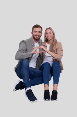 Zeminde oturan çift kalp işareti gösteriyor. Aşk İşareti Gösteren Çift. İlişki, Aile, Aşıklar, Arkadaşlar Konsepti. İmzala