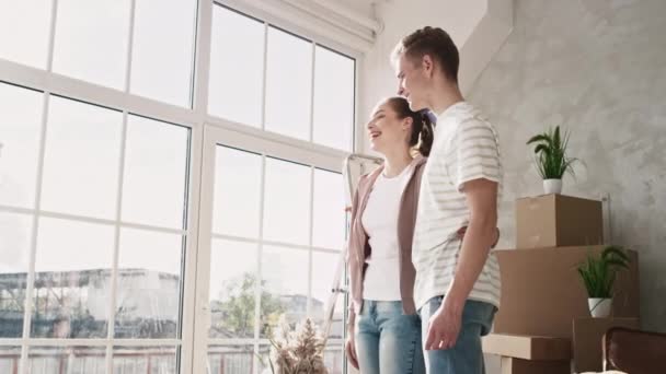 Couple regardant par la fenêtre là-bas nouvelle fille plate pointant. Couple déménagé dans une nouvelle maison. Couple Emménager par une journée ensoleillée. Tourné sur ROUGE — Video