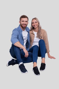 Zeminde oturan çift sarılıyor. Çift, cepheyi gözlüyor. İlişki, Aile, Aşıklar, Arkadaşlar Konsepti. İmzala