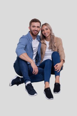 Zeminde oturan çift sarılıyor. Çift, cepheyi gözlüyor. İlişki, Aile, Aşıklar, Arkadaşlar Konsepti. İmzala