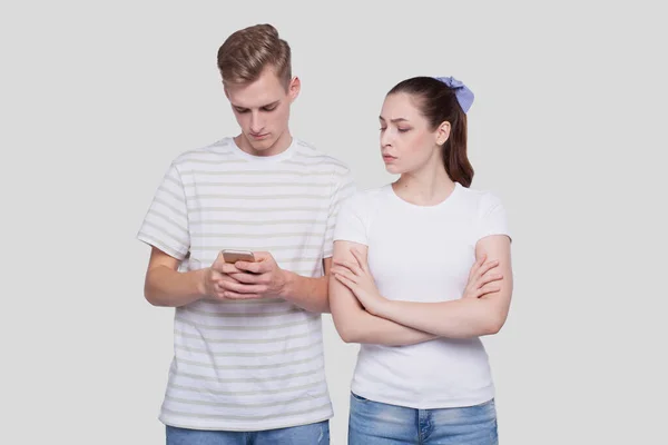 Man Chatting on Phone. Couple Using Phones Standing Isolated. Couple Shopping Online. Girl Watching in Man Phone. Secret in Phone. — Stock Photo, Image