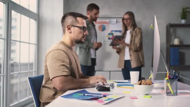 Mann, der im Büro hart arbeitet, reibt sich die Augen und nimmt die Brille ab. Müder Mann am PC im Büro mit Creative Team. Hard Workers Team. Schuss auf ROT. — Stockvideo