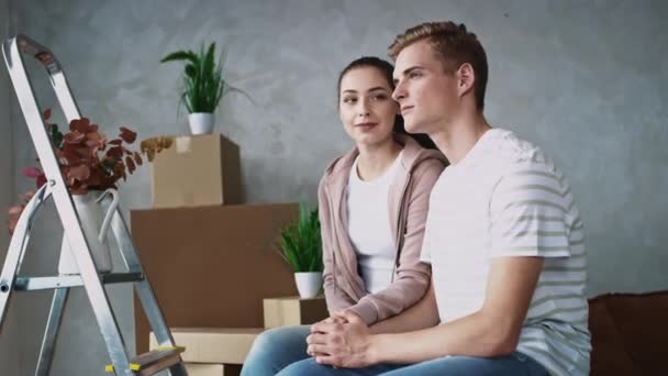 Coppia Guardando fuori dalla finestra in là nuovo appartamento. Un paio si sono trasferiti in una nuova casa. Un paio che si trasferiscono in una giornata di sole. Mani movimento girato sul rosso — Video Stock