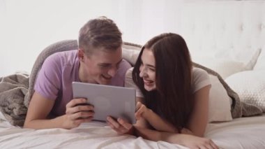 Yatakta Tablet kullanan çift. Yatakta Eğlenen Tabletli Çift. İnternetten Alışveriş.