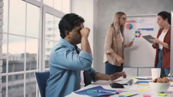 Indiano trabalhando duro no escritório esfregando os olhos tirando óculos. Homem Cansado Trabalhando no PC no escritório com a equipe criativa. Equipa de Trabalhadores. Tiro em vermelho. — Vídeo de Stock