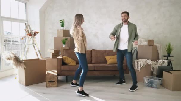 Pareja bailando en un nuevo hogar. Pareja se mudó en nuevo piso bailando feliz. Pareja celebrando la primera compra de casa. — Vídeos de Stock