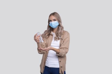 Tıbbi maske takan el dezenfektanı kullanan bir kız. El antiseptiği kullanan kız izole edildi. Medikal Cncept