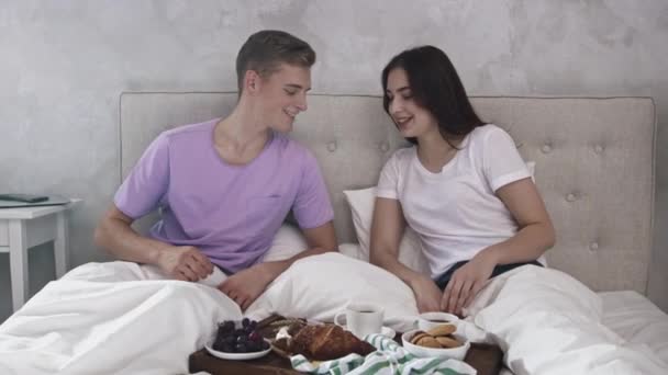 Couple Having Breakfast in Bed. Morning Breakfast. Girl Eating Crousant and Man Drinking Coffee. Shot on RED — Stockvideo