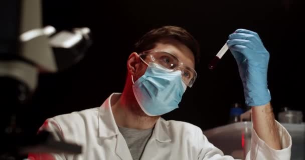 Docteur Examens de sang en chasse d'eau en laboratoire. Travailleur de laboratoire avec échantillon de sang. Test de Covid. Test sanguin. Homme travaillant avec masque médical, lunettes et gants. — Video