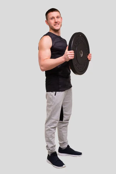 Sportivo con i pancake al bilanciere a mani nude. Un uomo che si allena con il bilanciere. Allenamento maschile. Sportsman Standing — Foto Stock