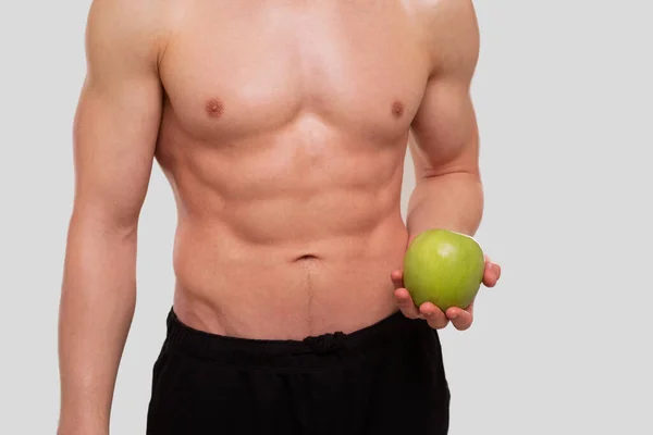 Mann hält Apple oben ohne. Sportler mit gesunder Ernährung in der Hand. Muskeln, Abs, Bizeps, Kern. Gesunde Ernährung, Gesunde Ernährung, Sport, Körper, Trainingskonzept — Stockfoto