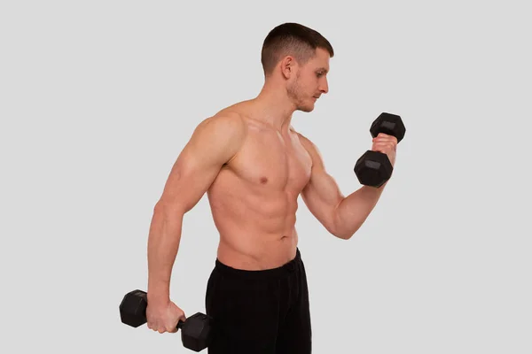 Mann oben ohne pumpt Bizeps mit Hantel. Sprinter beim Traning der Bizeps-Muskeln. Fitnessraum, Hebesportkonzept. — Stockfoto