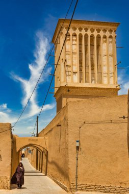 YAZD, İRAN - 27 Nisan 2015: İran 'da Yazd' ın dar sokaklarında kimliği belirsiz bir kadın yürüyor