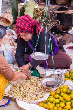 Woman in traditional dress sells vegetables at market of Inn Dain Khone Village, on Inle Lake.