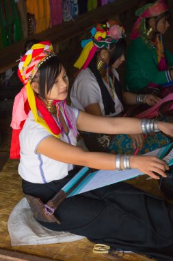Girl of the tribe Kayan (Padaung) in traditional clothing works to weaving cotton in his village near Lake Inle