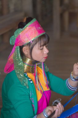 Girl of the tribe Kayan (Padaung) in traditional clothing works to weaving cotton in his village near Lake Inle