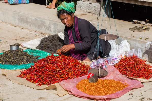 Woman in traditional dress sells vegetables at market of Inn Dain Khone Village, on Inle Lake.
