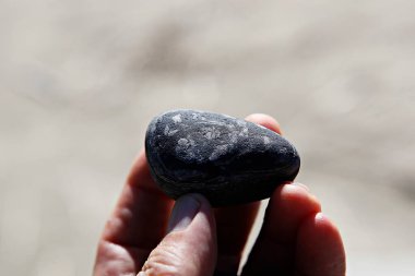 Siyah taşı tutan insanın eline yaklaş.