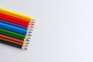 Beyaz arkaplanda çok renkli kalemler. Renkli boya kalemleri çizgisi. Üst görünüm, kopyalama alanı ile çapraz konum. Çizim için sanatçının ekipman kavramı.
