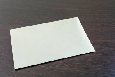 Müdürün yeni ofis masasının koyu lakaplı ahşap yüzeyine yatay olarak yerleştirilmiş boş bir kağıt. Harf ya da logo yerleştirme için boş bir yerleşim planı. Dokulu eski kağıt yüzeyi