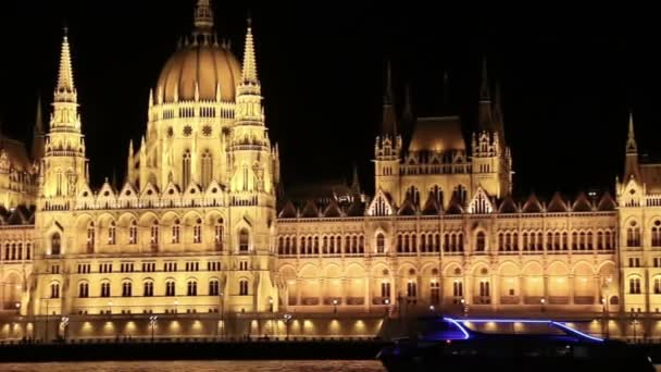 Parliament in Budapest at night while sailing on a boat on the river Danube. — Stock Video