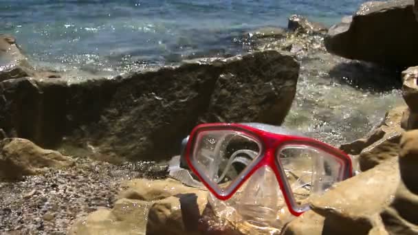 Masque de natation posé sur le rivage lavé par les vagues — Video