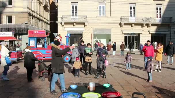 Bologne, Italie - 1er janvier 2015 : Des enfants stupéfaits par d'énormes bulles de savon dans la rue à Bologne, en Italie. Art de rue — Video