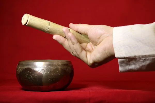 Cuenco de canto tibetano y mano sobre fondo rojo — Foto de Stock