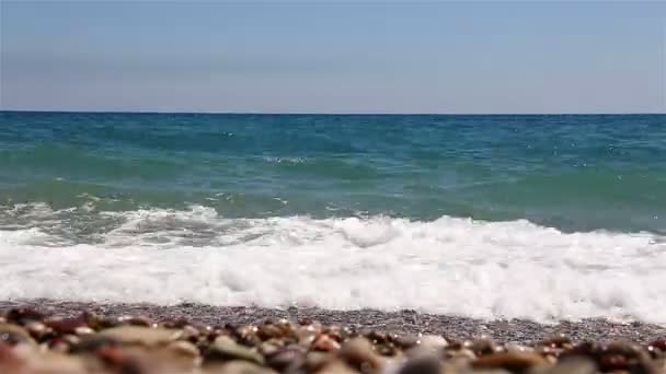 A hullámok a tenger, a gyönyörű kavicsos strand a háttérben. — Stock videók