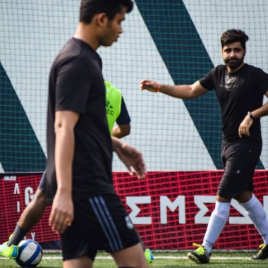 Yeni Delhi, Hindistan - 19 Temmuz 2019 - Kötü bir futbol sahasında bölgesel Derby şampiyonasında yerel futbol takımının futbolcuları. Stadyumun çimen yeşili sahasında sıcak bir futbol maçı var.