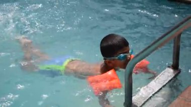 Havuzda yüzen mutlu Hintli çocuk, sıcak yaz tatillerinde hava tüpüyle birlikte yüzen çocuk, büyük bir havuzda yüzen çocuk..