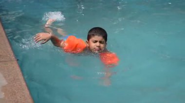 Havuzda yüzen mutlu Hintli çocuk, sıcak yaz tatillerinde hava tüpüyle birlikte yüzen çocuk, büyük bir havuzda yüzen çocuk..