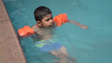 Havuzda yüzen mutlu Hintli çocuk, sıcak yaz tatillerinde hava tüpüyle birlikte yüzen çocuk, büyük bir havuzda yüzen çocuk..
