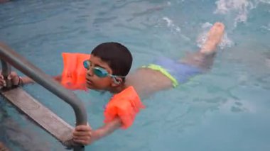 Havuzda yüzen mutlu Hintli çocuk, sıcak yaz tatillerinde hava tüpüyle birlikte yüzen çocuk, büyük bir havuzda yüzen çocuk..