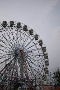 Delhi, Hindistan 'da Dussehra Mela sırasında çok renkli Dev Tekerlek' in yakın çekimi. Dev tekerlek salıncağının alt görüntüsü. Akşam vakti renkli kamaraları olan dönme dolap..