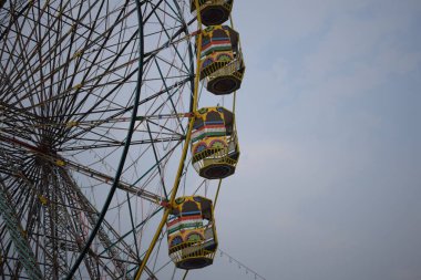 Delhi, Hindistan 'da Dussehra Mela sırasında çok renkli Dev Tekerlek' in yakın çekimi. Dev tekerlek salıncağının alt görüntüsü. Akşam vakti renkli kamaraları olan dönme dolap..
