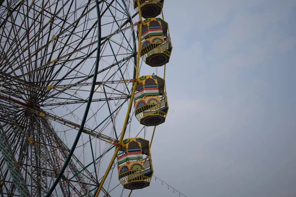Delhi, Hindistan 'da Dussehra Mela sırasında çok renkli Dev Tekerlek' in yakın çekimi. Dev tekerlek salıncağının alt görüntüsü. Akşam vakti renkli kamaraları olan dönme dolap..