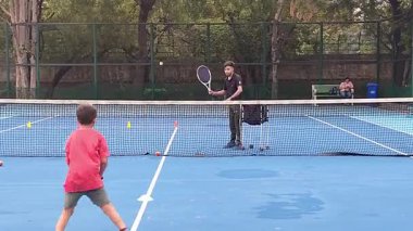 Delhi, Hindistan, 17 Şubat 2025 - Maha Open için kil tenis kortunda antrenörlük yapan genç tenisçiler, yaklaşan turnuva için küçük tenis oyuncuları antrenman yapıyor