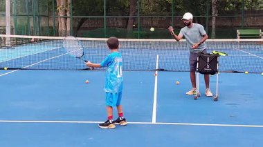 Delhi, Hindistan, 17 Şubat 2025 - Maha Open için kil tenis kortunda antrenörlük yapan genç tenisçiler, yaklaşan turnuva için küçük tenis oyuncuları antrenman yapıyor