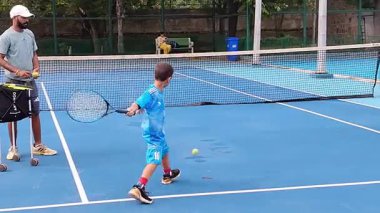 Delhi, Hindistan, 17 Şubat 2025 - Maha Open için kil tenis kortunda antrenörlük yapan genç tenisçiler, yaklaşan turnuva için küçük tenis oyuncuları antrenman yapıyor