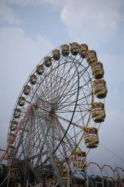 Delhi, Hindistan 'da Dussehra Mela sırasında çok renkli Dev Tekerlek' in yakın çekimi. Dev tekerlek salıncağının alt görüntüsü. Akşam vakti renkli kamaraları olan dönme dolap..