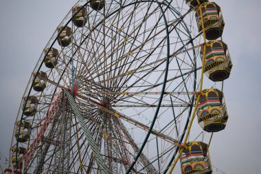Delhi, Hindistan 'da Dussehra Mela sırasında çok renkli Dev Tekerlek' in yakın çekimi. Dev tekerlek salıncağının alt görüntüsü. Akşam vakti renkli kamaraları olan dönme dolap..
