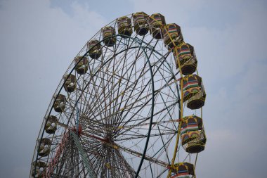 Delhi, Hindistan 'da Dussehra Mela sırasında çok renkli Dev Tekerlek' in yakın çekimi. Dev tekerlek salıncağının alt görüntüsü. Akşam vakti renkli kamaraları olan dönme dolap..