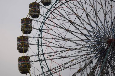 Delhi, Hindistan 'da Dussehra Mela sırasında çok renkli Dev Tekerlek' in yakın çekimi. Dev tekerlek salıncağının alt görüntüsü. Akşam vakti renkli kamaraları olan dönme dolap..