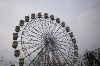Delhi, Hindistan 'da Dussehra Mela sırasında çok renkli Dev Tekerlek' in yakın çekimi. Dev tekerlek salıncağının alt görüntüsü. Akşam vakti renkli kamaraları olan dönme dolap..