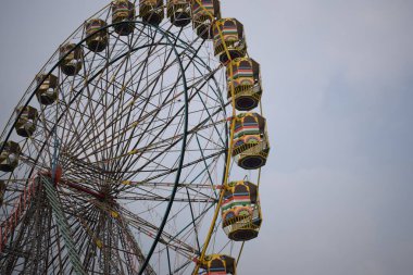 Delhi, Hindistan 'da Dussehra Mela sırasında çok renkli Dev Tekerlek' in yakın çekimi. Dev tekerlek salıncağının alt görüntüsü. Akşam vakti renkli kamaraları olan dönme dolap..